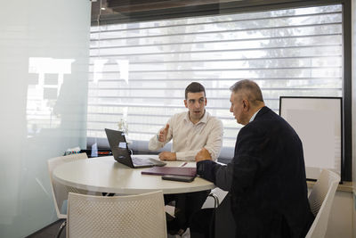 Businessman with colleague discussing at desk in office