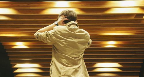 Low angle view of man standing in illuminated room