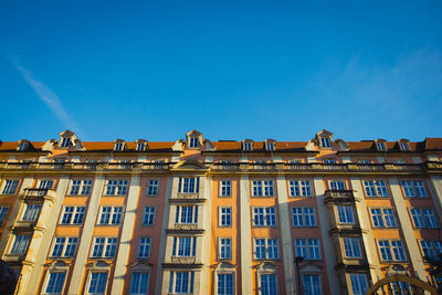 Low angle view of yellow building against blue sky