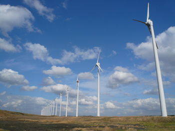 Low angle view of windmill on field against sky