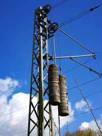 Low angle view of electricity pylon against clear blue sky