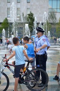 Boys and police in city against fountain