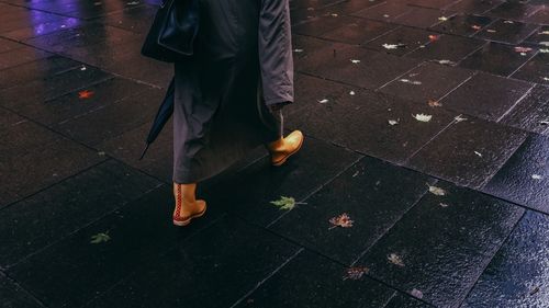 Low section of person walking on wet footpath