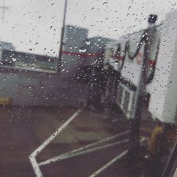 Close-up of wet glass window against sky