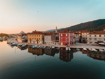 Reflection of buildings in sea against clear sky during sunset