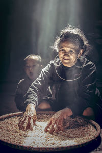 Smiling senior woman cleaning grain in container