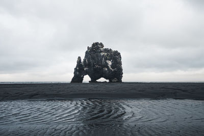 Rock formation on beach against sky