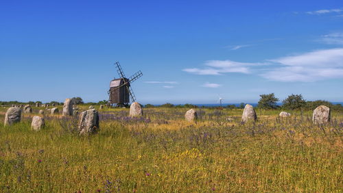 Viking stone ship burial and old windmill in oland island by beautiful day, gettlinge, sweden