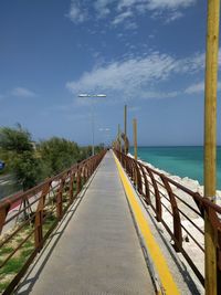 Walkway by sea against sky