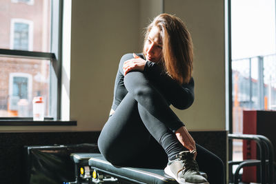 Portrait of resting young brunette woman in sport active wear in the fitness club gym