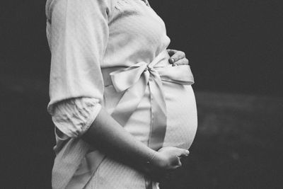 Close-up of pregnant woman standing on field