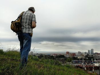 Man standing on the mountain and looking at cityscape against the foggy sky