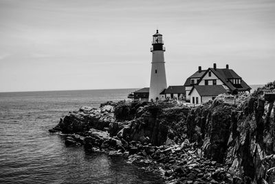 Lighthouse amidst sea and buildings against sky