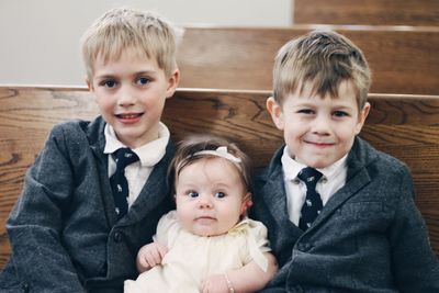 Portrait of brothers in formalwear with baby girl