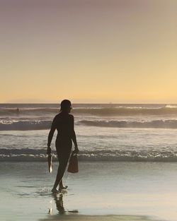 Full length of man on beach against sky during sunset