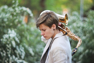 Side view of young woman with saxophone standing at park