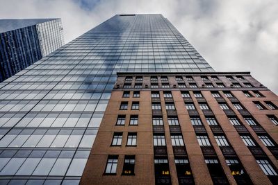 Low angle view of modern building with partial historic facade against sky