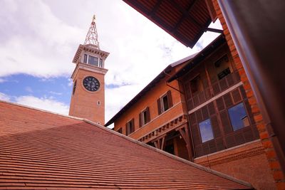 Low angle view of clock tower amidst buildings against sky