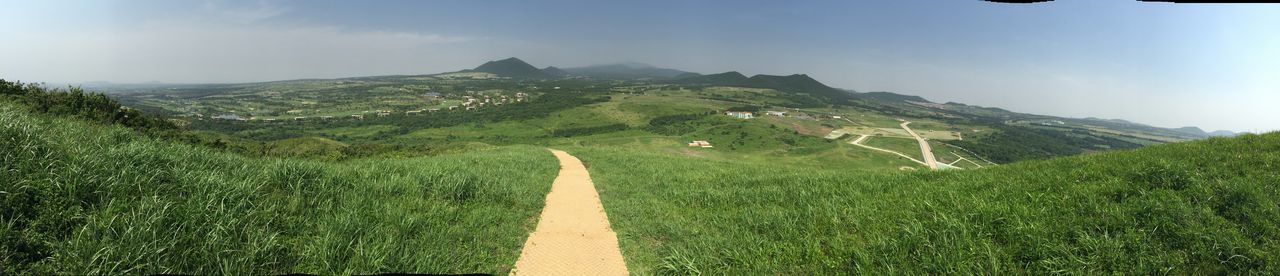 the way forward, mountain, grass, sky, green color, landscape, road, tranquility, tranquil scene, nature, scenics, beauty in nature, diminishing perspective, field, vanishing point, day, sunlight, non-urban scene, growth, outdoors