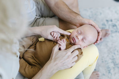 Woman carrying baby on lap sitting by man at home