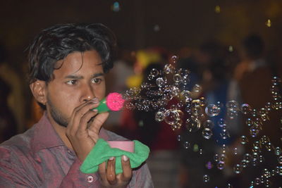 Man blowing bubbles at night