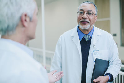 Male doctors talking while standing in corridor at hospital