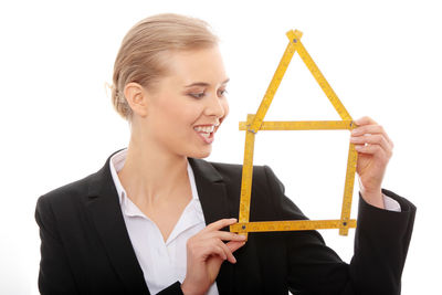 Smiling young woman holding umbrella against white background