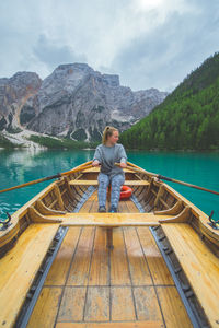 Woman rowing boat in lake against mountains