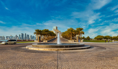 Fountain in city against blue sky