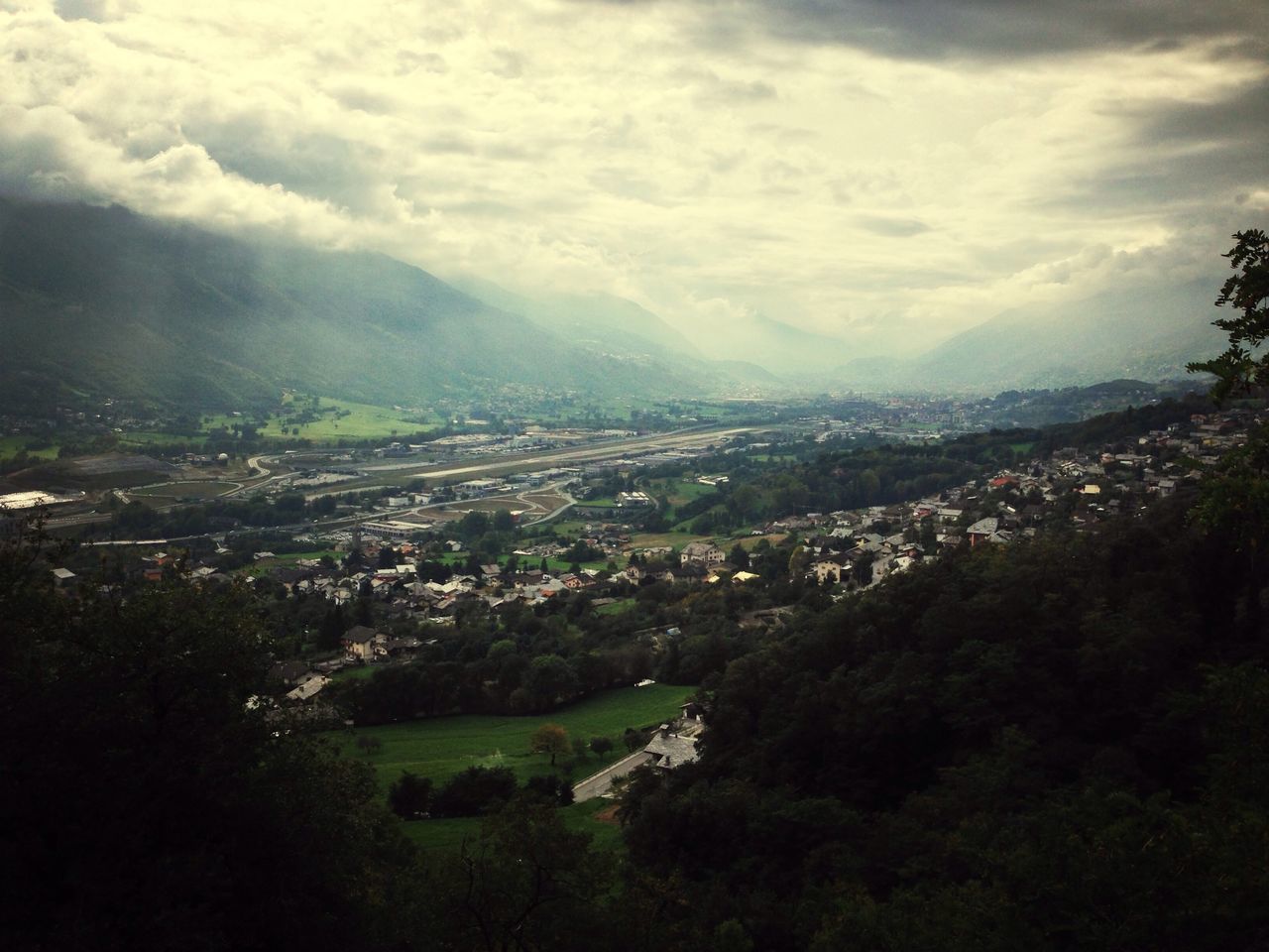 tree, landscape, sky, high angle view, building exterior, scenics, built structure, architecture, beauty in nature, green color, cloud - sky, nature, tranquil scene, cityscape, tranquility, mountain, aerial view, house, residential district, city