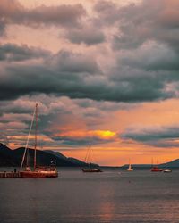 Sailboats sailing on sea against sky during sunset