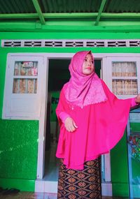 Portrait of woman standing against pink wall