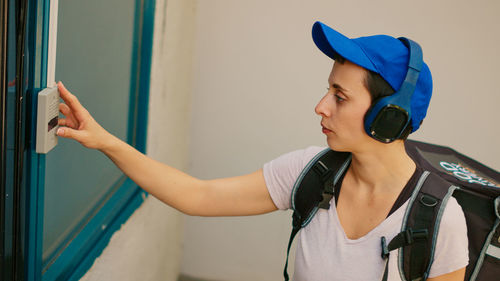 Side view of young woman wearing hat standing at home