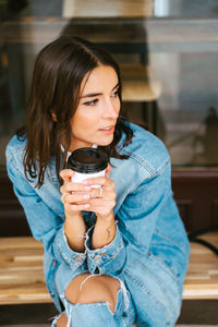 Young woman looking down while sitting against wall