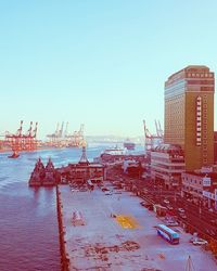 Cranes in city against clear sky