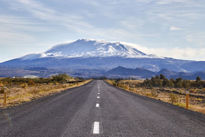 Road leading towards mountain range against sky