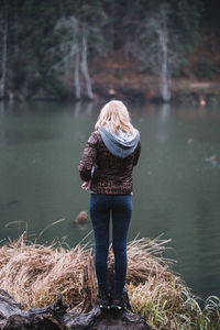 Rear view of woman standing by lake