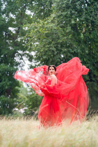 Woman with red umbrella standing on field