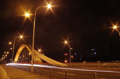 Light trails on road against sky at night