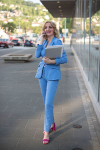 Portrait of smiling young woman using mobile phone in city