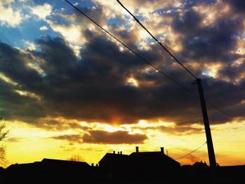 Low angle view of power lines against cloudy sky