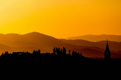 Silhouette buildings in a city  against sky during sunset