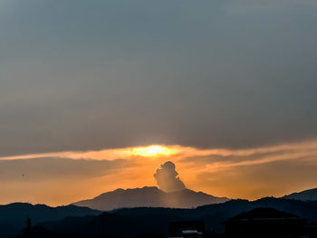 Scenic view of silhouette mountains against orange sky