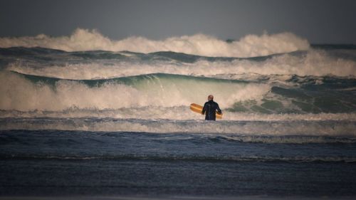 Man surfing in sea against sky