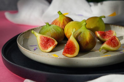 Figs fruits placed on a small plate on a table with a tablecloth and sunshine