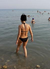 Rear view of woman wearing bikini walking towards sea