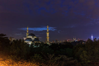 Illuminated buildings in city against sky at night