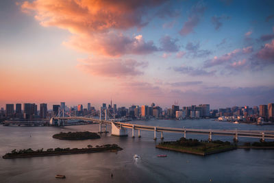 Bridge over river with buildings in background during sunset