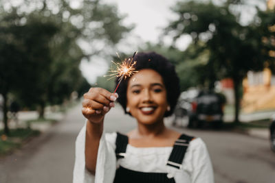 Portrait of smiling young woman standing on street in city