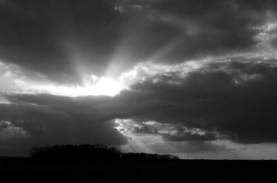 Silhouette of field against cloudy sky